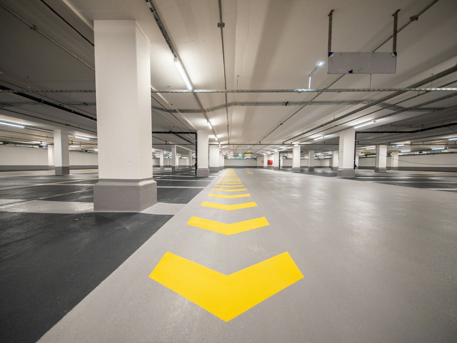 Yellow directional arrow painted on a resin-coated car park floor.