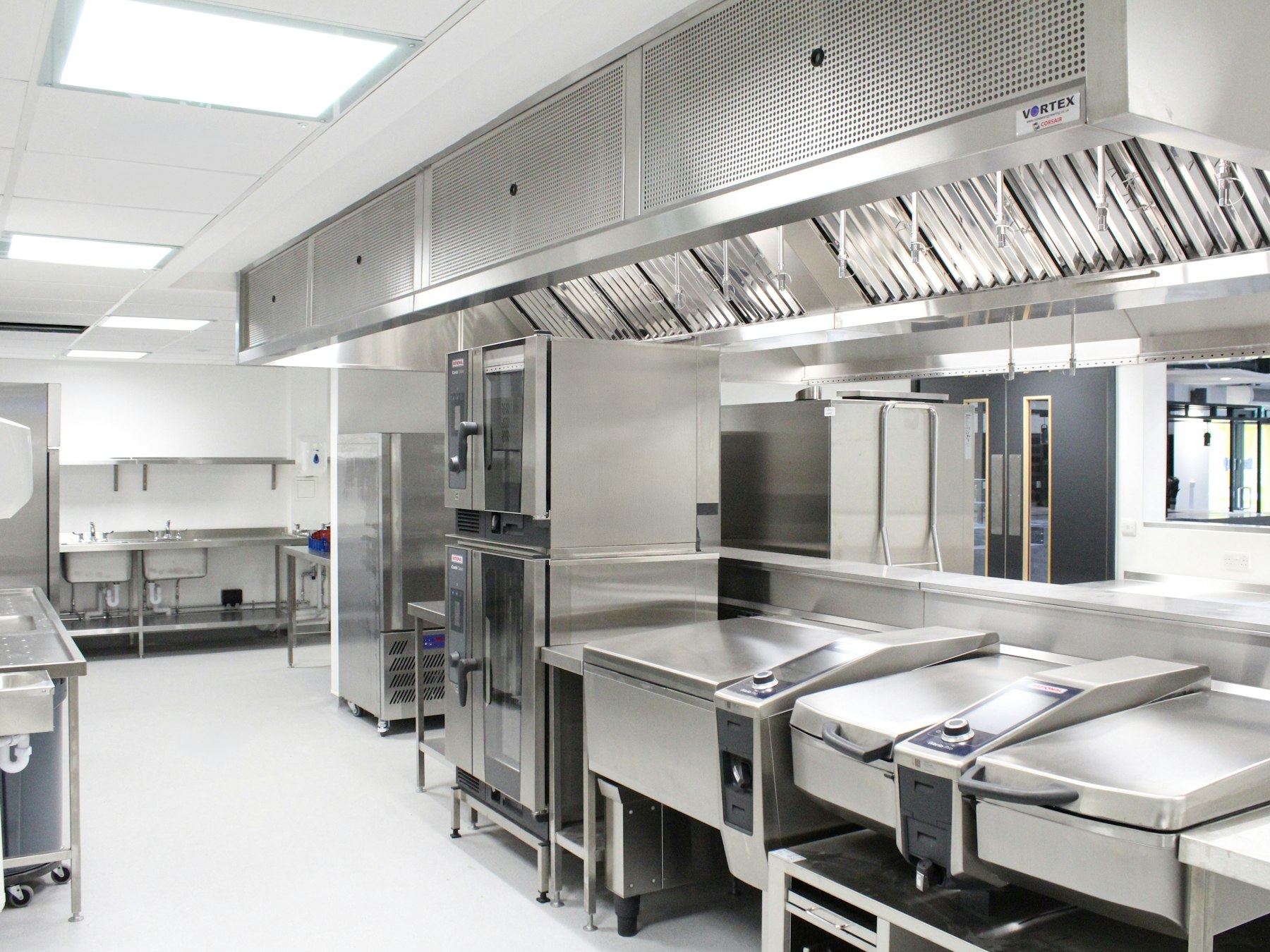 Bright commercial kitchen with stainless steel appliances and a light seamless floor