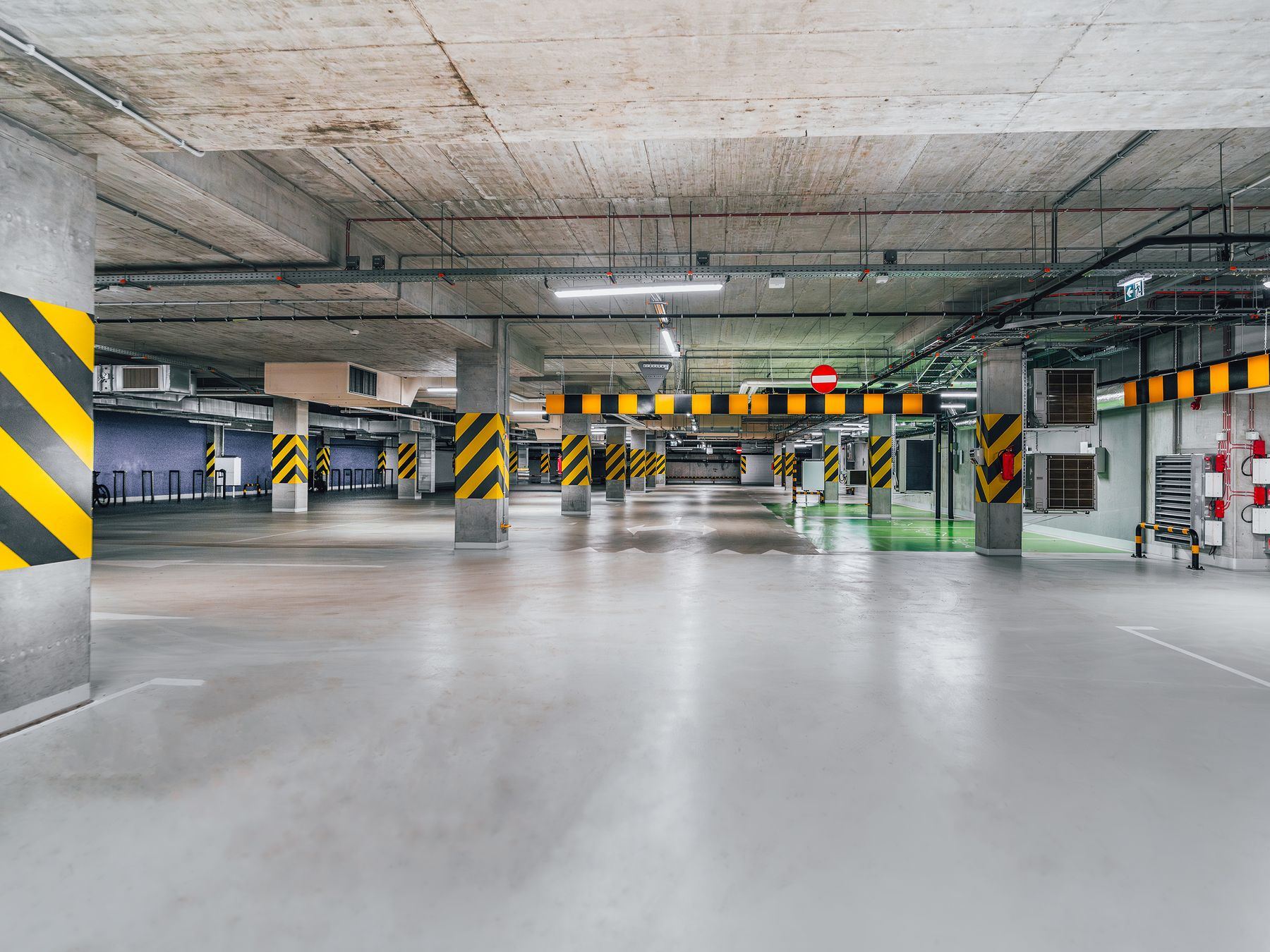 Empty underground car park with grey resin flooring and yellow hazard markings.