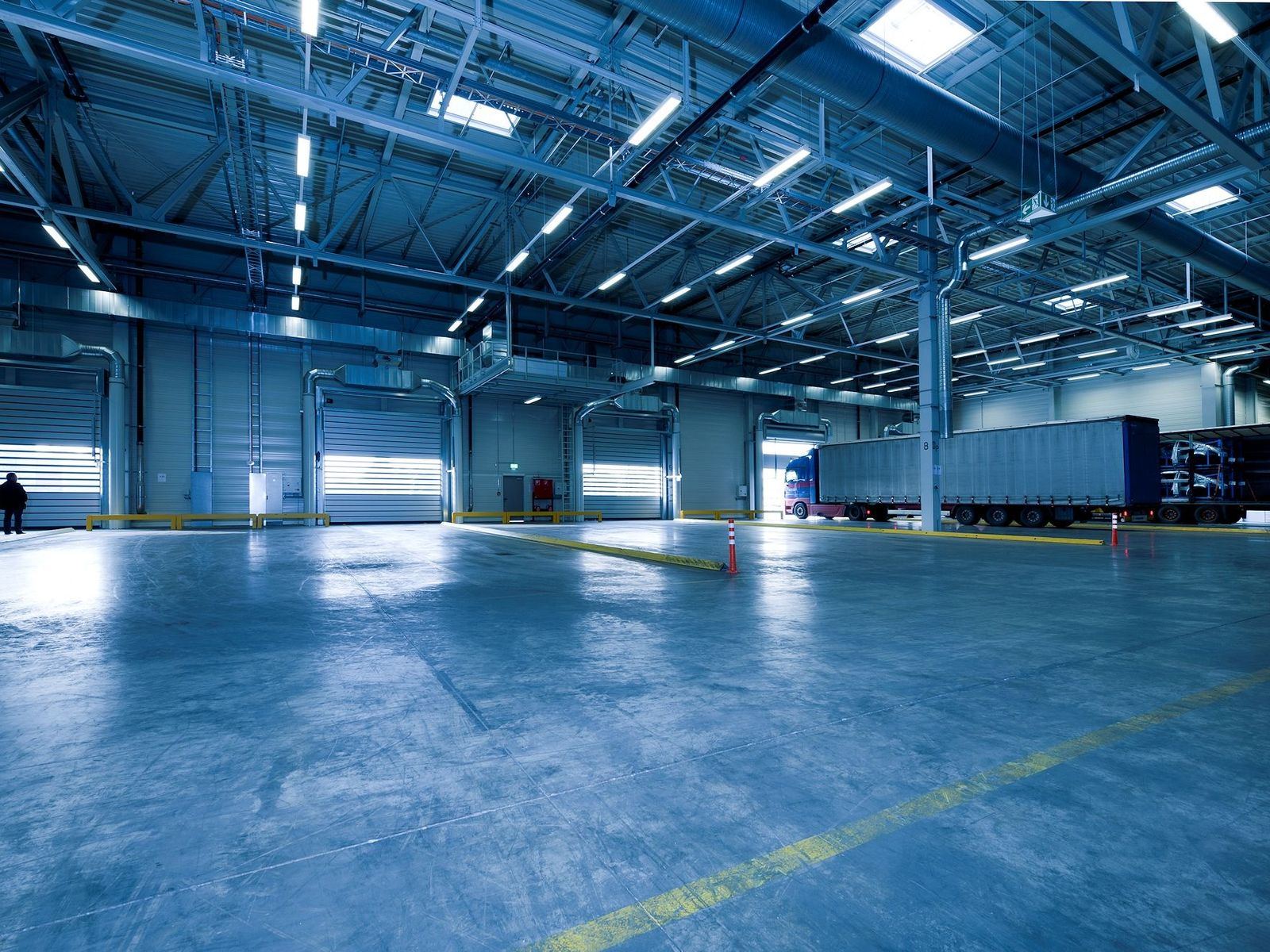 Blue-tinted industrial warehouse with loading dock and truck
