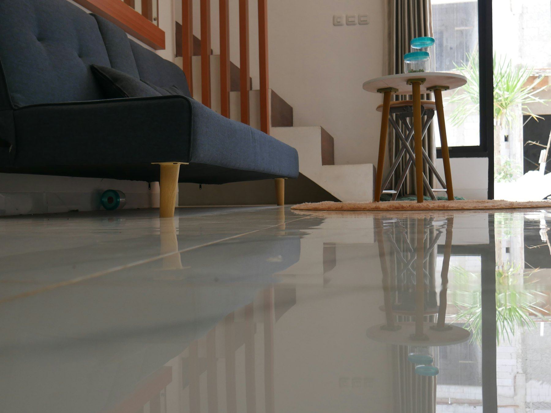 Living room with a sofa and glossy polished floor near a staircase.